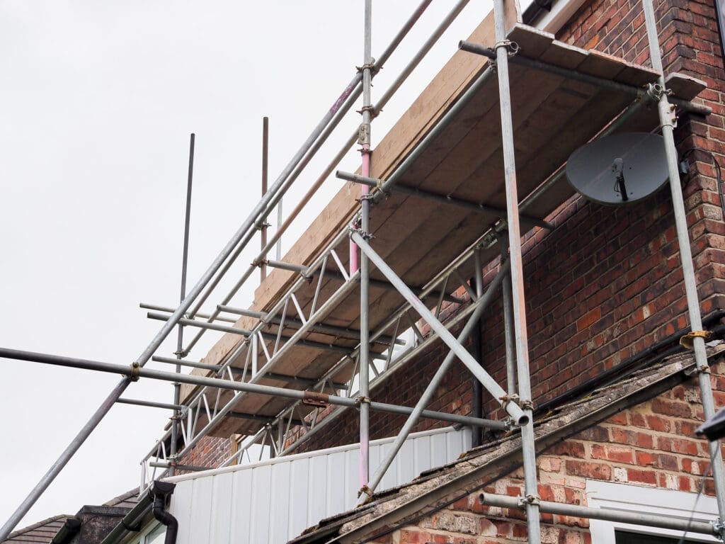 Scaffolding on brick building for construction with satellite dish attached
